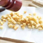 Croutons mit Salz und Pfeffer würzen